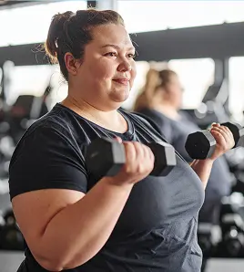 overweight woman using dumbbells at the gym