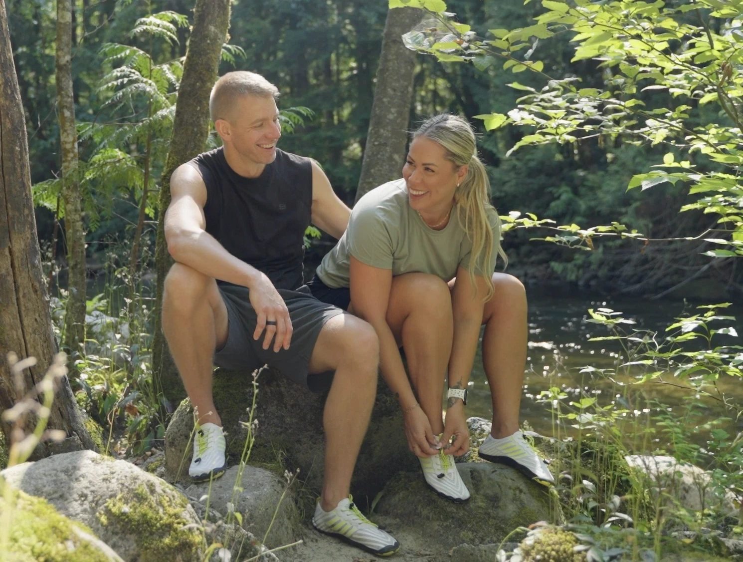 Two people sitting on rocks in the woods wearing Grounded Footwear® Freedom shoes