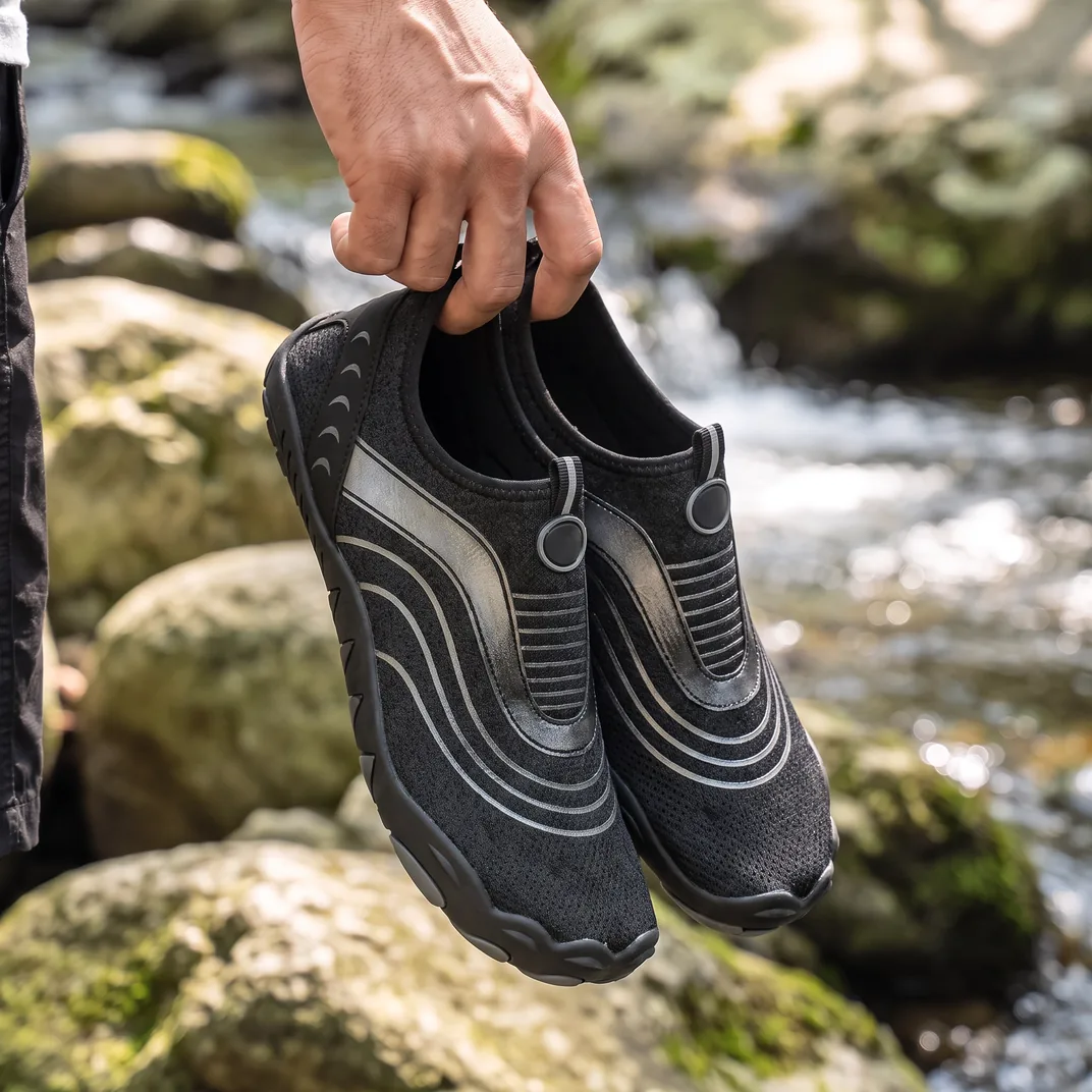 A man carrying a pair of Glide in Black Onyx by a stream
