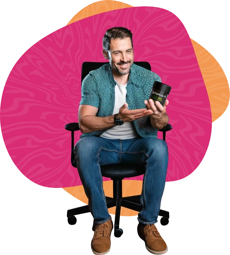 A man sitting in an office chair, holding a jar of gummies and gesturing toward it in a way that shows he's talking about the product.