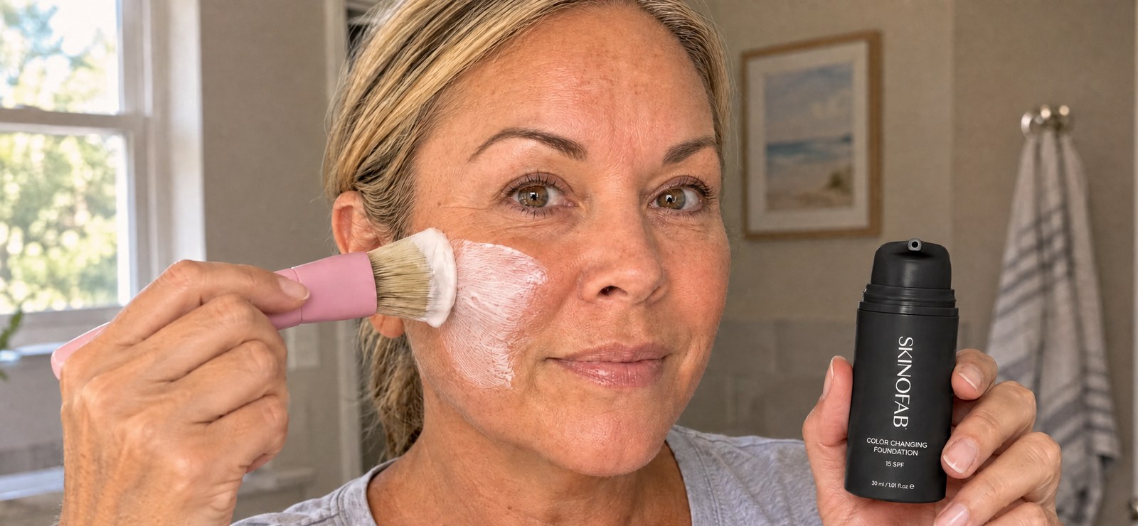 Woman blending Skinofab foundation onto her cheek while holding the bottle
