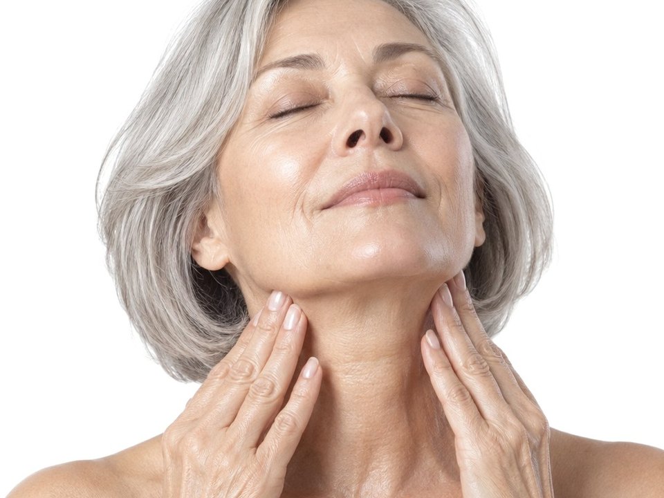 A woman smoothing the serum down her neck