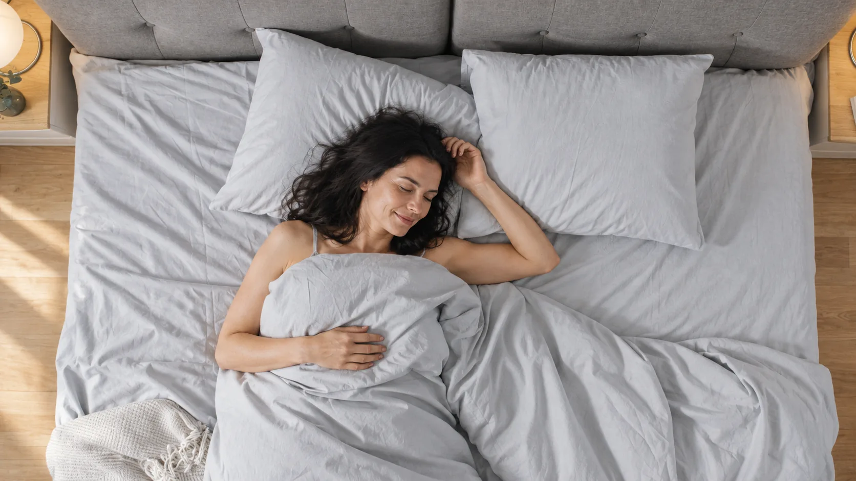 Woman sleeping on a bed made with grey Velin Silver Thread sheets