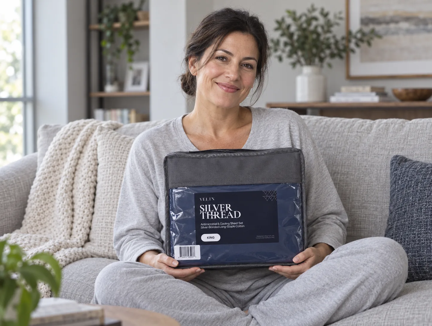 Customer holding a Velin Silver Thread sheet set on her sofa