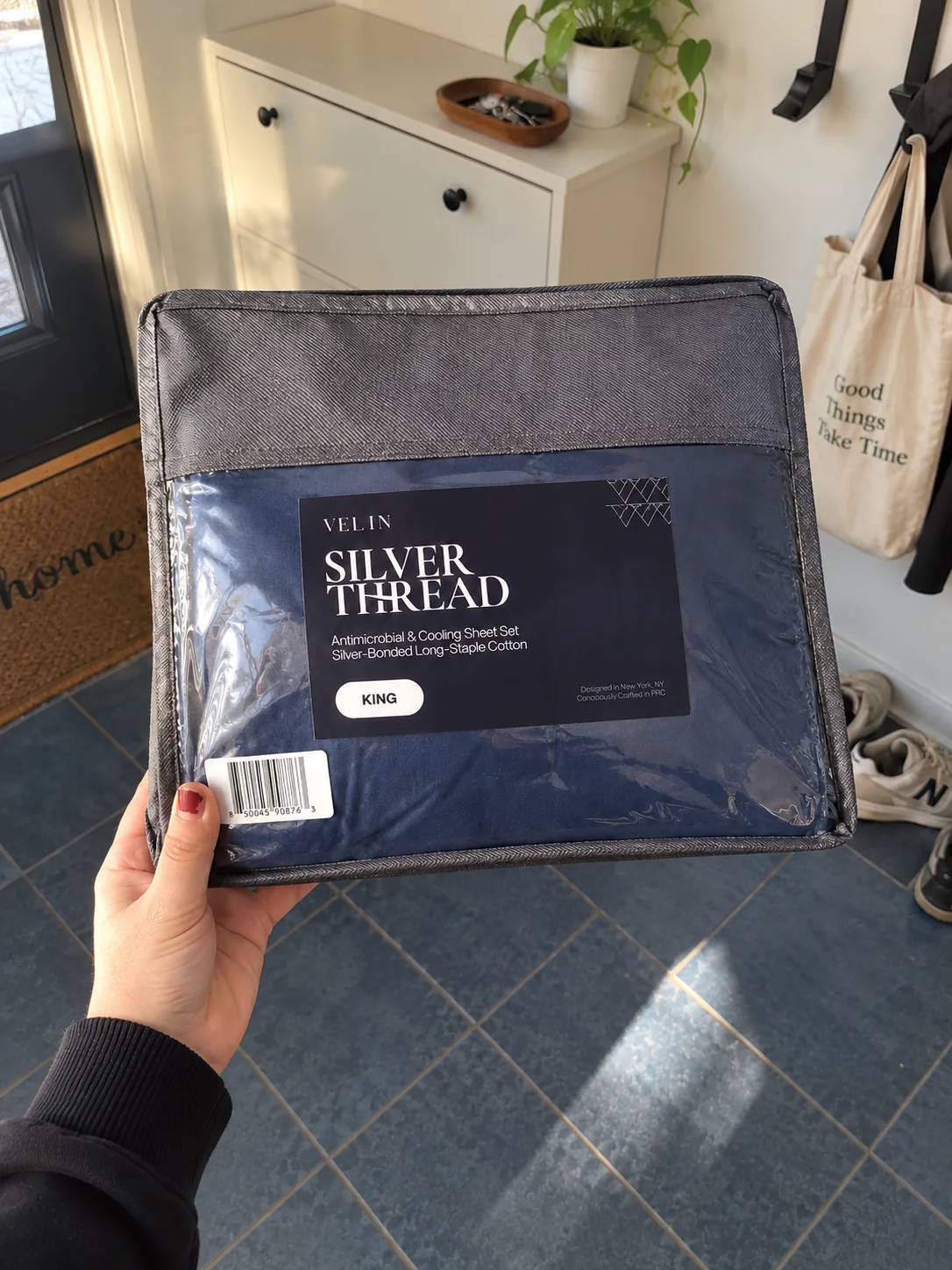 Navy Velin Silver Thread sheet set held up beside a made bed