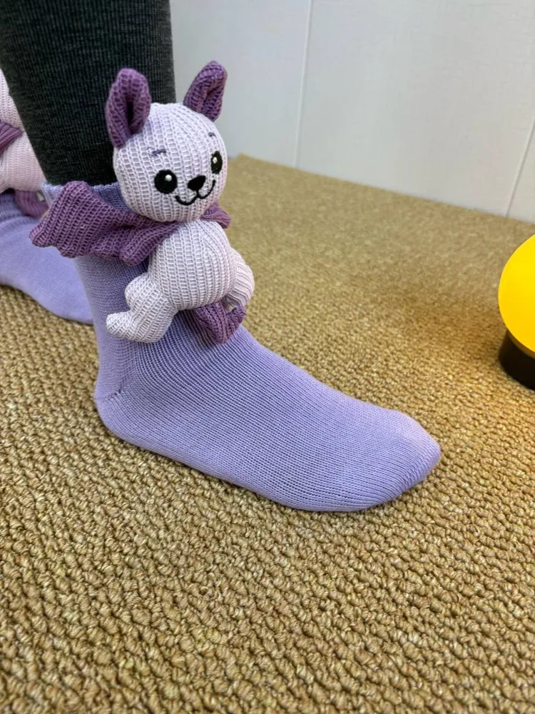 Purple Echo the Bat socks worn on a sofa
